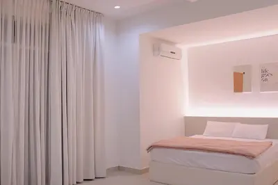 a white room with a bed and a window at Alle House by Wei in Kampong Gurun