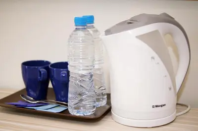 a bottle of water on a tray next to a blender at Good Luck Inn in Ayer Itam