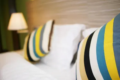a bed with two striped pillows and a lamp at Good Luck Inn in Ayer Itam