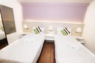 two beds in a room with white walls at Good Luck Inn in Ayer Itam