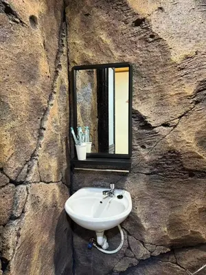 a sink in a stone wall with a mirror at MR B hotel in Bukit Mertajam