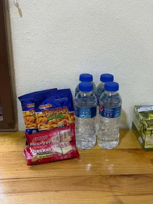 three bottles of water and snacks on a wooden floor at MR B hotel in Bukit Mertajam