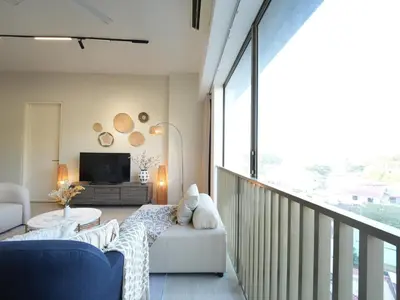 a living room with a couch and a tv on a balcony at Cozy Seaview Escape 2BR 6pax bythesea bathroom in Pulau Pinang
