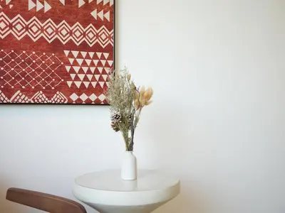 a white vase with flowers on a table next to a painting at Cozy Seaview Escape 2BR 6pax bythesea bathroom in Pulau Pinang