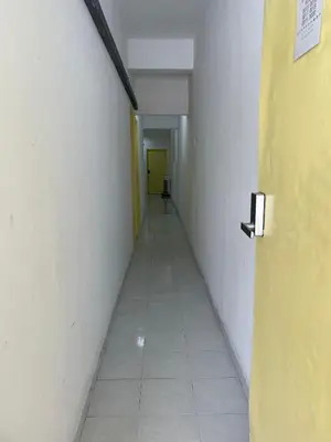 a hallway with a yellow door and white walls and a room at Rest N Go CM in Ipoh