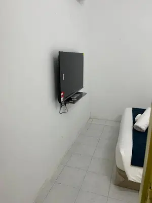a living room with a tv on a white wall at Rest N Go CM in Ipoh