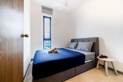 a bedroom with a bed with a blue blanket and a window at M22 #CityView SeaView #Georgetown #35 in George Town