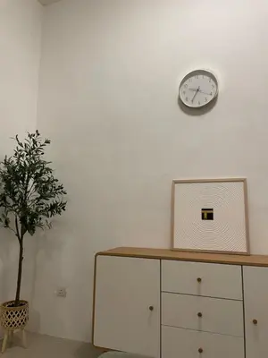 a white wall with a clock and a potted plant at Orked Homestay 2 Parit Buntar in Parit Buntar