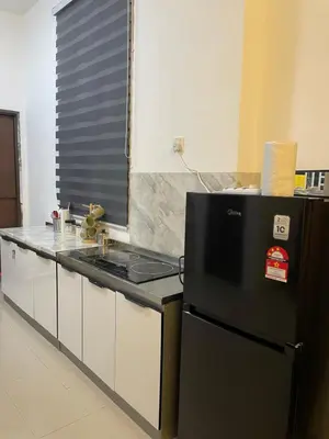 a kitchen with a stove and a black refrigerator at Orked Homestay 2 Parit Buntar in Parit Buntar