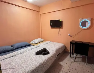 a bedroom with two beds and a tv on the wall at TY Youth Hostel in Sekincan