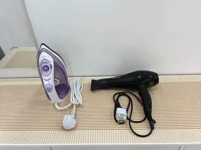 a hair dryer and a blow dryer on a bed at BM Alma Aeonjusco Auto City Homestay in Bukit Mertajam