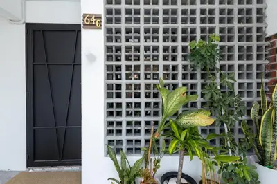 a white lattice wall next to a door with plants at Casa Celia - Pet allowed private parking studio in Ipoh