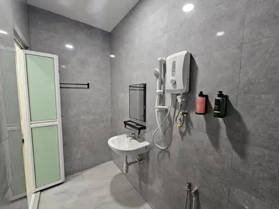 a bathroom with a sink and a soap dispenser on the wall at Roomstay KOBANAS in Ipoh