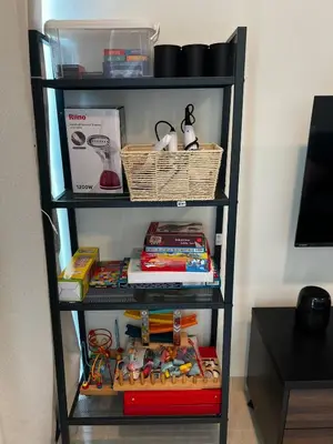 a black book shelf filled with books and toys at Ether 665 Homestay in Sekincan