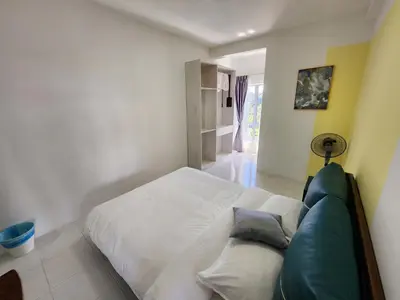 a bedroom with a white bed and a blue couch at Cameron Highland 910 The Garden 3BR 6 Pax in Brinchang