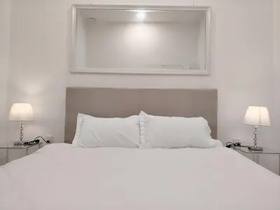 a bedroom with a white bed with two lamps at Executive White Houze in Kepala Batas