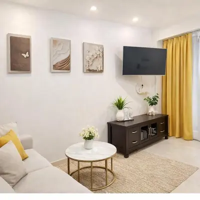 a living room with a couch and a tv on a wall at 3 Bedrooms Single Storey Terrace at Taman Inderawasih ,12mins to Penang Bridge , 5mins to Sunway Carnival Mall in Butterworth