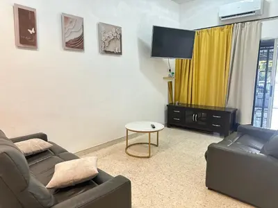 a living room with two couches and a flat screen tv at 3 Bedrooms Single Storey Terrace at Taman Inderawasih ,12mins to Penang Bridge , 5mins to Sunway Carnival Mall in Butterworth
