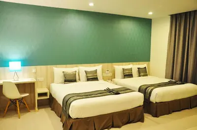two beds in a hotel room with a green wall at Valya Hotel, Ipoh in Ipoh