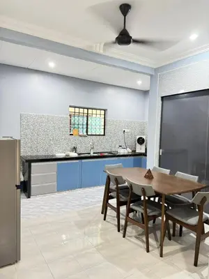 a kitchen with a wooden table and blue cabinets at Teratak Perdana in Sungai Petani