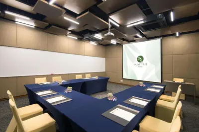 a conference room with blue tables and chairs and a screen at Olive Tree Hotel Penang in Bayan Lepas