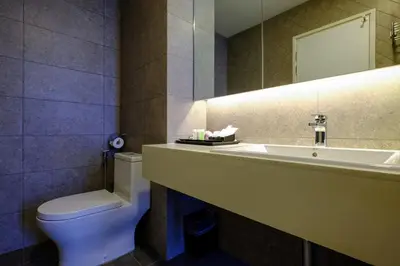a bathroom with a sink and a toilet and a mirror at Penang Beachfront Seaview Residences in Tanjong Tokong