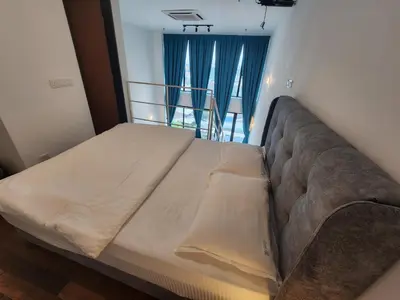 a large bed in a bedroom with blue curtains at Sunrise Gurney Spacious Comfort Suite - Penang Gurney Drive in George Town