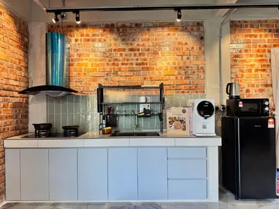 a kitchen with white cabinets and a brick wall at Ruyu 44 TownVilla 5R4B 18pax Bbq KTV Pool Table in Ipoh