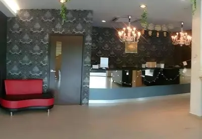 a lobby with a red chair and a table at Hotel Grand Court Inn in Sungai Besar