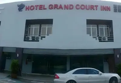 a white car parked in front of a hotel grand court inn at Hotel Grand Court Inn in Sungai Besar