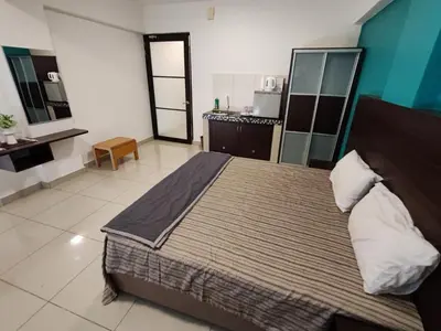 a bedroom with a large bed and a kitchen at KIMNA HOME at MARINA HEIGHT in Lumut