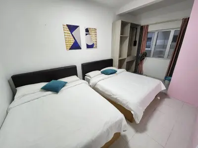 two beds in a room with white sheets and blue pillows at Sweet Home G12 Emerald Avenue in Brinchang