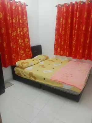 a small bed in a room with red curtains at Homestay Saadiah in Sungai Besar