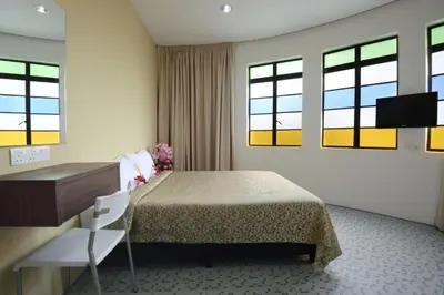 a hotel room with a bed and a desk and windows at Swing & Pillows - Grand Inn George Town Penang in George Town