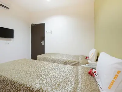 a hotel room with two beds and a television at Swing & Pillows - Grand Inn George Town Penang in George Town