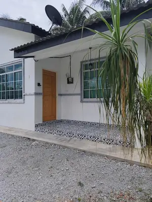 a white house with a door and a palm tree at Rumah Huda in Bukit Mertajam