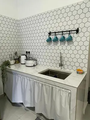 a kitchen with a sink and a white tiled wall at Rumah Huda in Bukit Mertajam