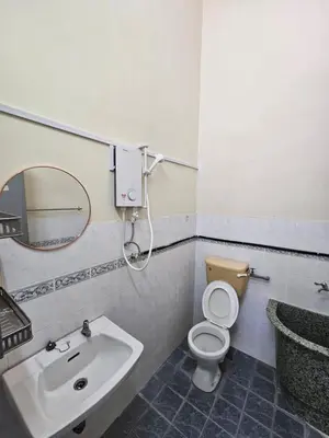 a bathroom with a sink and a toilet and a mirror at Pera House Hostel in Ipoh