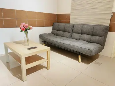 a living room with a couch and a table with a vase of flowers at Cozy Suite with Twin Beds & Lounge in Nibung Tebal