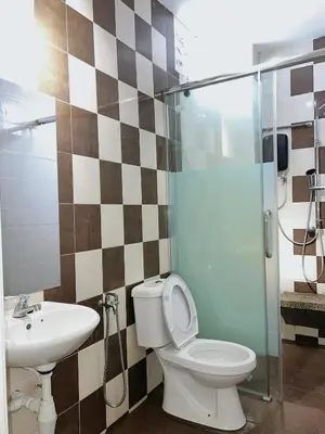 a bathroom with a toilet and a sink and a shower at Cozy Suite with Twin Beds & Lounge in Nibung Tebal