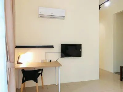 a room with a desk and a tv on a wall at Cozy Family Room with Large Balcony in Nibung Tebal