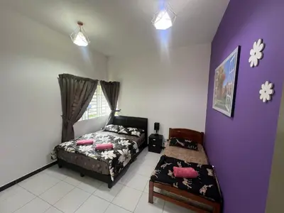 a bedroom with a bed and a chair and a window at StayIndah Homestay Cameron Highlands in Tanah Rata