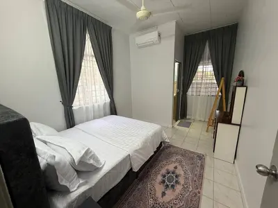 a bedroom with a bed and two windows and a rug at Wareesha Homestay, Corner Lot With Netflix in Padang Serai