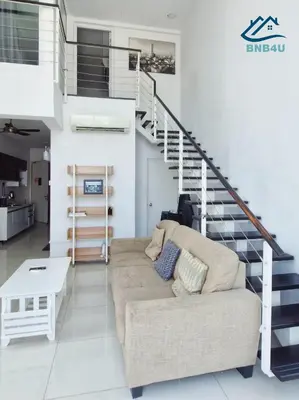 a living room with a couch and a staircase at Duplex Comfort Stay in George Town in George Town