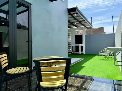 a patio with chairs and a table and grass at \u5feb\u4e50\u5ba2\u6808 Sentosa Cottage in Raub