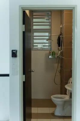 a bathroom with a toilet and a glass shower door at Bright & Airy Double-Storey Retreat 4BR in Simpang Ampat