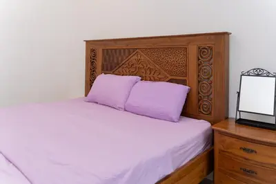 a bed with two purple pillows and a wooden headboard at Bright & Airy Double-Storey Retreat 4BR in Simpang Ampat