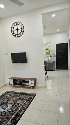 a living room with a clock on a white wall at Neera Rest House in Gua Sai