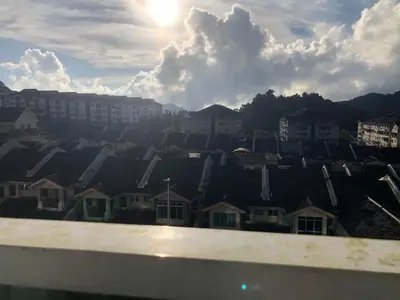 a view of a city with houses and the sun at Rayyan'Homestay PMCJ in Tanah Rata