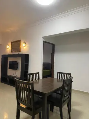 a dining room table with two chairs and a television at Risma Homestay in Batu Ferringhi